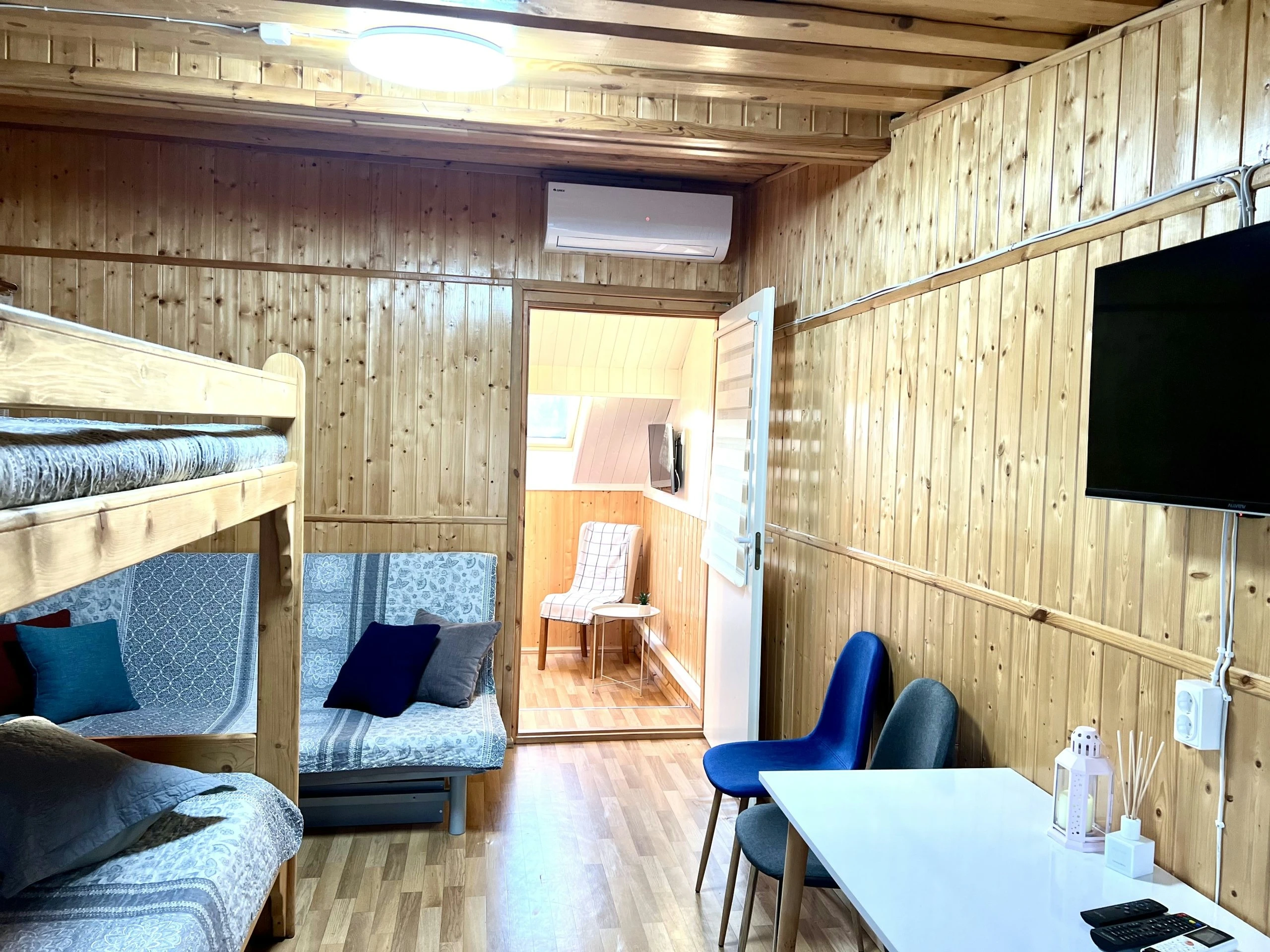 7D kotedžas – Medinis kambarys su dviaukšte lova, minkštais baldais, stalu ir sieniniu televizoriumi