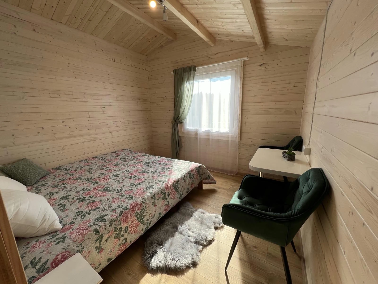 5 namelis – Šviesus medinis miegamasis su gėlėta lovatiese, rašomuoju stalu ir žaliu krėslu