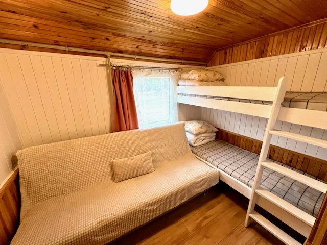 6 namelis – Medinis kambarys su smėlio spalvos sofa ir balta dviaukšte lova
